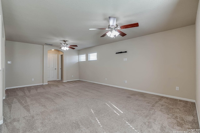 carpeted spare room with arched walkways, visible vents, baseboards, and ceiling fan