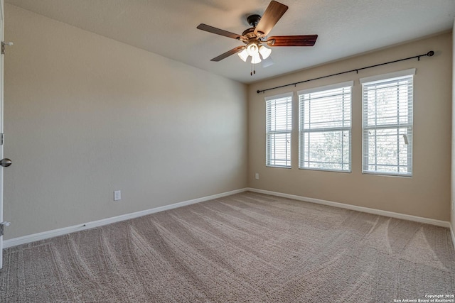 carpeted spare room featuring baseboards and ceiling fan