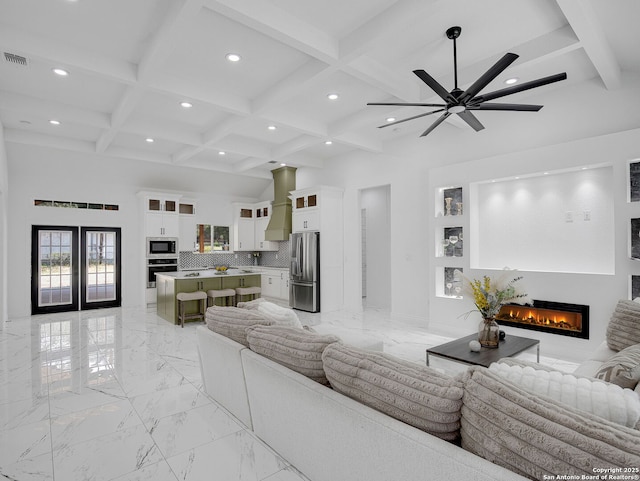 living room featuring beam ceiling, a glass covered fireplace, marble finish floor, and coffered ceiling