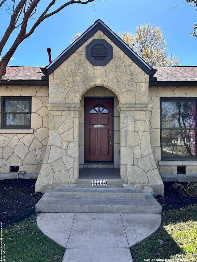 property entrance with stone siding and roof with shingles