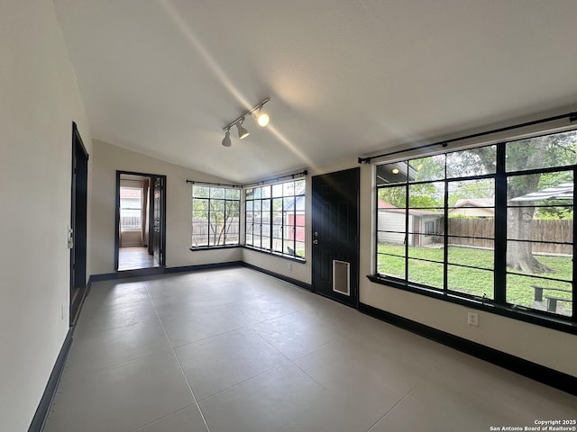 spare room with rail lighting, tile patterned floors, baseboards, and vaulted ceiling