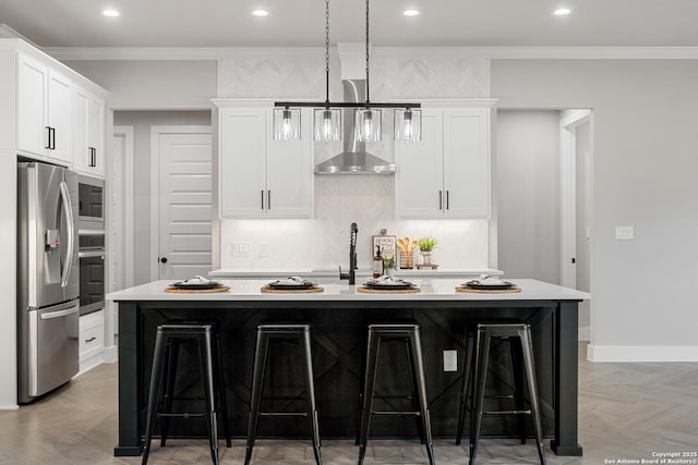 kitchen featuring a breakfast bar, light countertops, ornamental molding, appliances with stainless steel finishes, and a kitchen island with sink