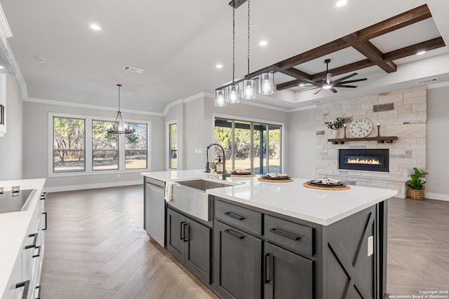 kitchen featuring visible vents, a sink, stainless steel dishwasher, ceiling fan with notable chandelier, and open floor plan