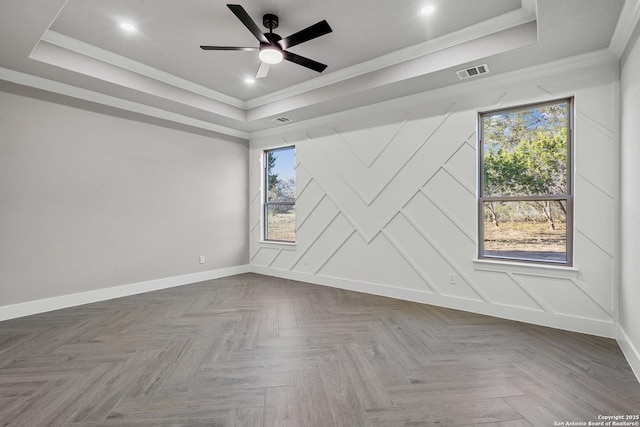 spare room featuring a raised ceiling, visible vents, and a wealth of natural light