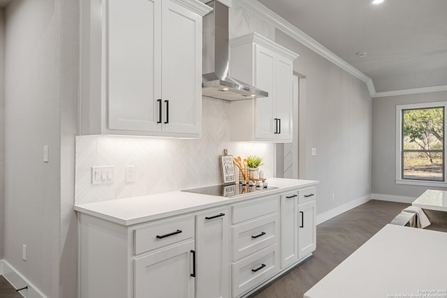 kitchen with light countertops, wall chimney range hood, tasteful backsplash, and ornamental molding