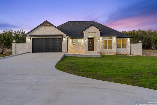 view of front of property featuring a front yard, driveway, roof with shingles, an attached garage, and stone siding