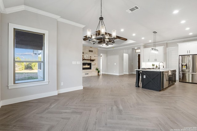 kitchen featuring visible vents, stainless steel refrigerator with ice dispenser, crown molding, open floor plan, and a chandelier