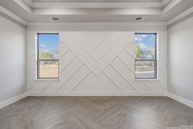 unfurnished room with visible vents, a raised ceiling, baseboards, and ornamental molding