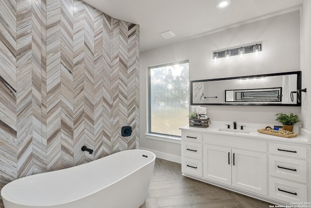 bathroom with recessed lighting, a freestanding bath, vanity, and baseboards