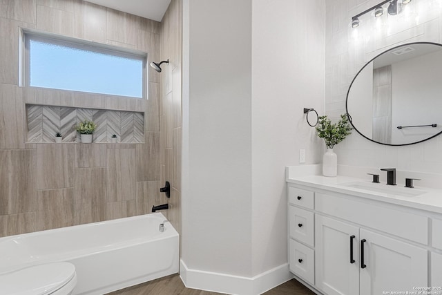 full bath with baseboards, toilet, vanity, wood finished floors, and washtub / shower combination