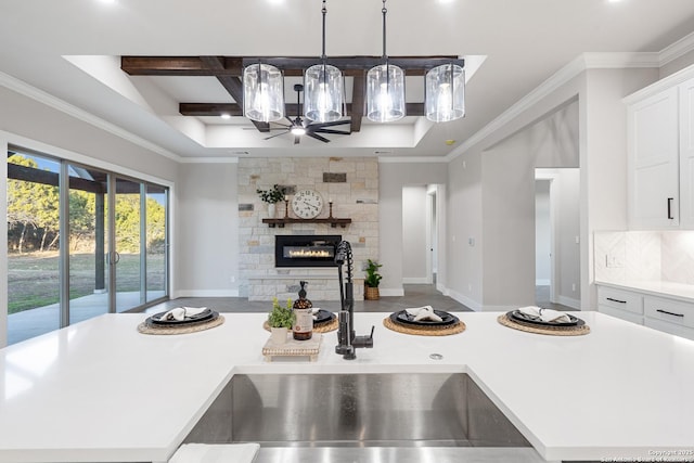 kitchen featuring open floor plan, light countertops, ornamental molding, coffered ceiling, and a sink