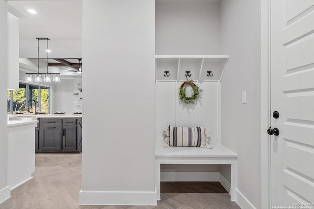 mudroom featuring beam ceiling, recessed lighting, baseboards, and a sink