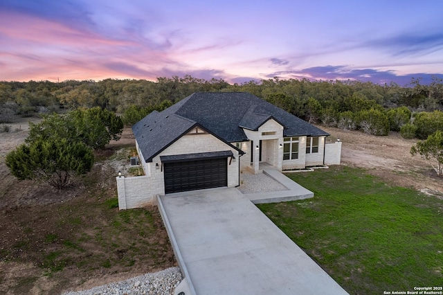 view of front facade with a front yard, a garage, stone siding, and driveway