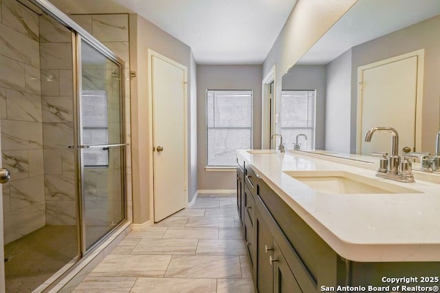 bathroom featuring a shower stall, double vanity, baseboards, and a sink