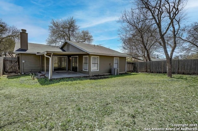 rear view of property featuring a yard, a fenced backyard, a chimney, and a patio area