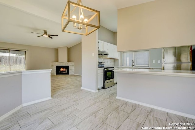 kitchen with under cabinet range hood, light countertops, ceiling fan with notable chandelier, appliances with stainless steel finishes, and white cabinetry