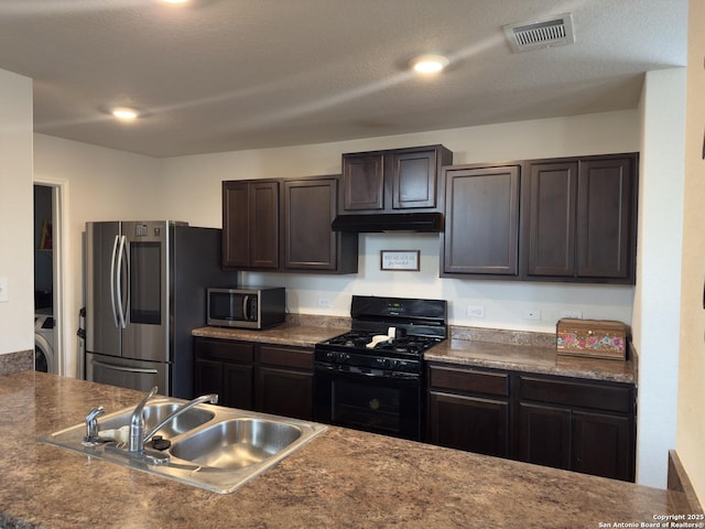 kitchen with visible vents, a sink, washer / clothes dryer, dark brown cabinetry, and appliances with stainless steel finishes