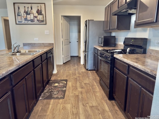 kitchen with under cabinet range hood, light wood-type flooring, light countertops, stainless steel appliances, and a sink