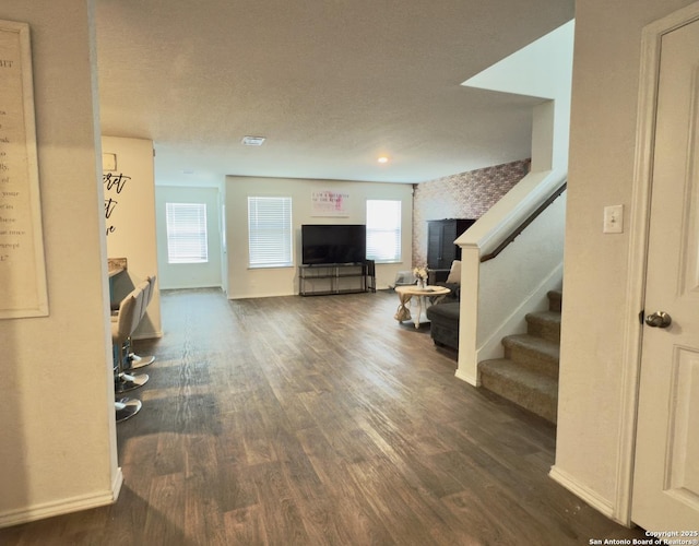 living area featuring stairway, wood finished floors, baseboards, and a textured ceiling