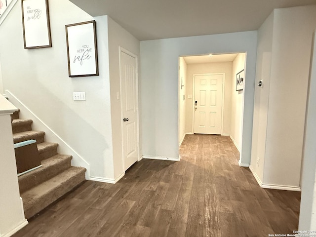 hall featuring dark wood finished floors, stairs, and baseboards