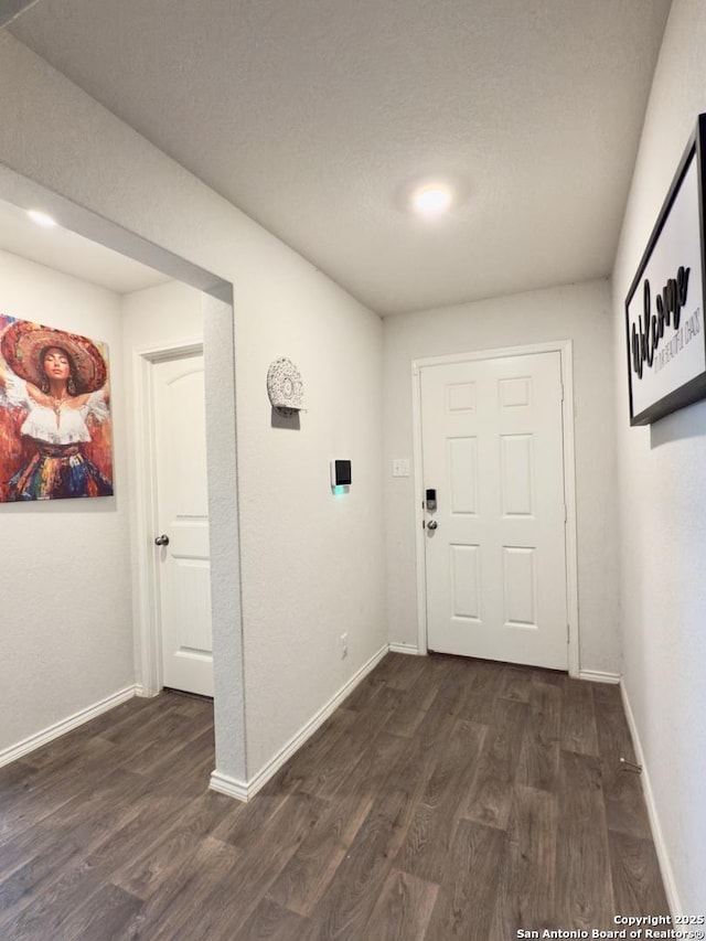 corridor with dark wood-style floors and baseboards