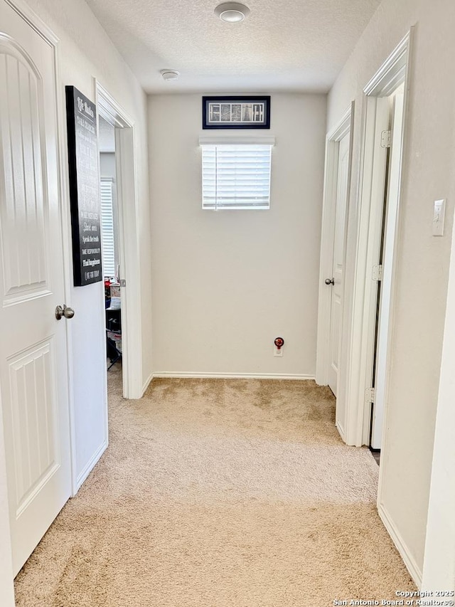 hall featuring baseboards, a textured ceiling, and carpet