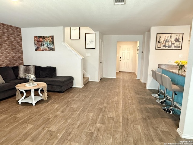 living area with stairway, baseboards, visible vents, and wood finished floors