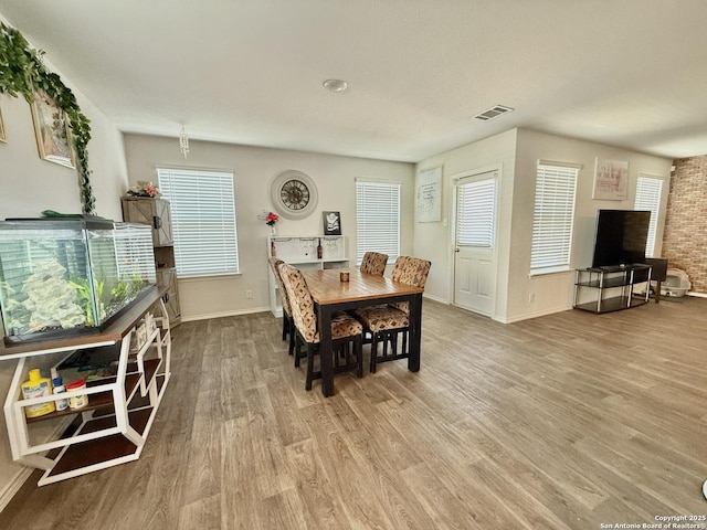 dining area with visible vents, baseboards, and wood finished floors