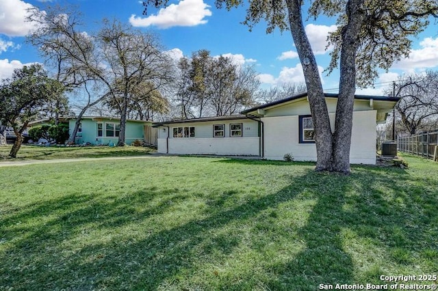 view of front of property featuring central air condition unit, a front lawn, and fence