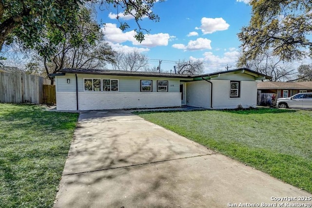 view of front of house with a front lawn, fence, brick siding, and driveway