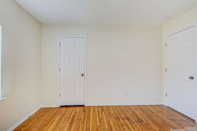 spare room with baseboards and light wood finished floors