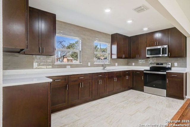 kitchen with tasteful backsplash, visible vents, light countertops, appliances with stainless steel finishes, and a sink