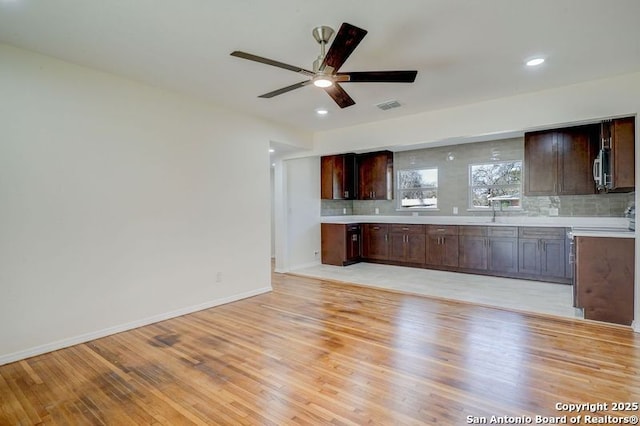 kitchen featuring decorative backsplash, ceiling fan, light countertops, and light wood-style floors