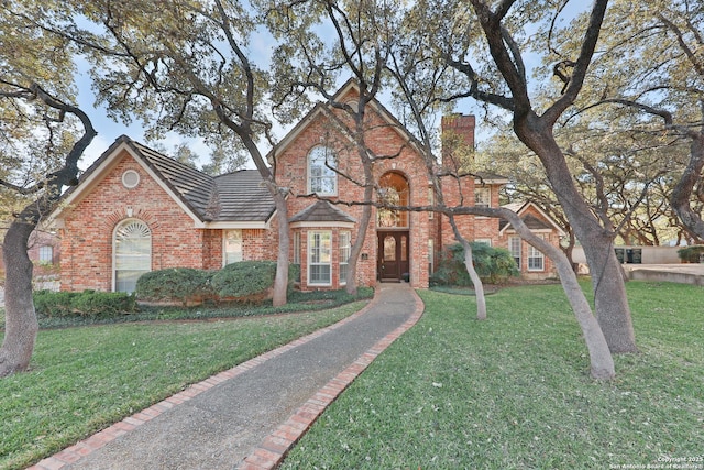 view of front of property featuring a front lawn, brick siding, and a chimney