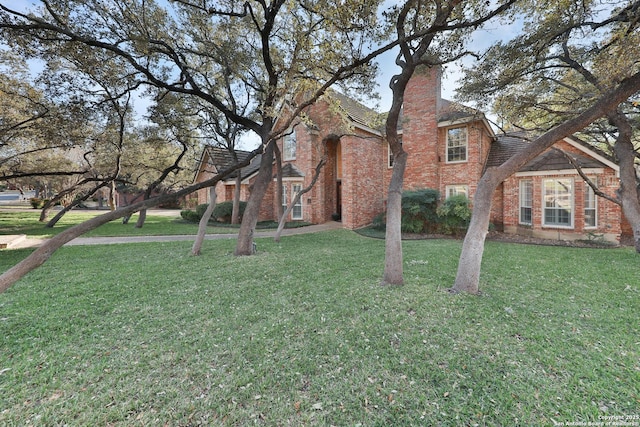 exterior space with brick siding, a chimney, and a front yard