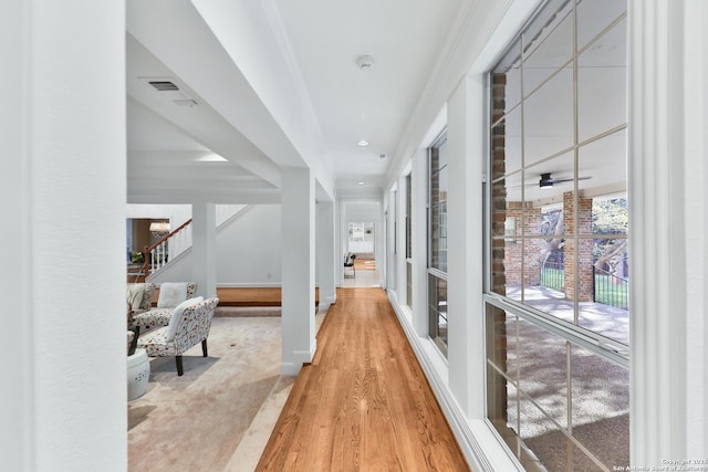 hallway with stairway, baseboards, visible vents, and wood finished floors