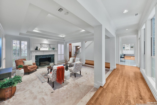 living room with visible vents, baseboards, stairs, a tray ceiling, and a fireplace