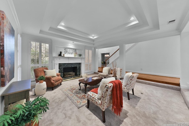 living room featuring stairway, baseboards, visible vents, a premium fireplace, and a raised ceiling