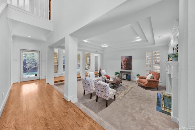 carpeted living area featuring a fireplace with flush hearth, plenty of natural light, baseboards, and a tray ceiling