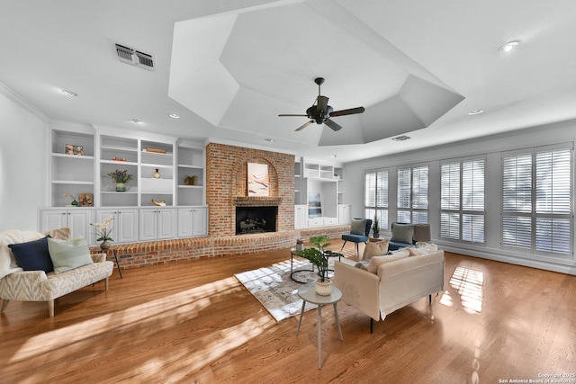 living area featuring visible vents, a healthy amount of sunlight, a raised ceiling, and wood finished floors