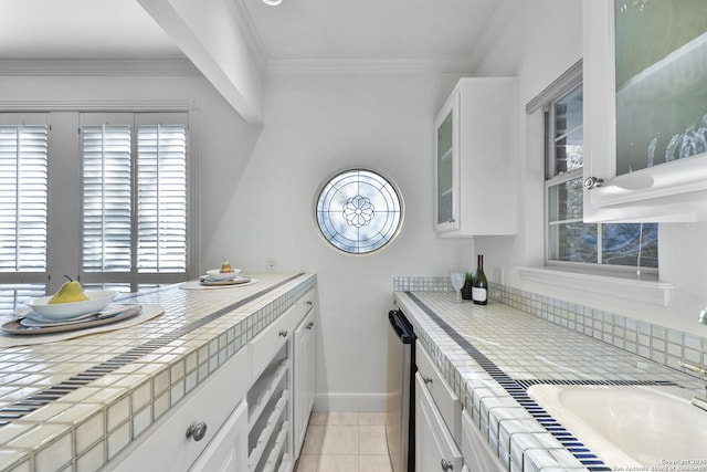 kitchen with tile counters, ornamental molding, and white cabinetry