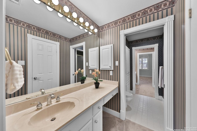 bathroom with baseboards, toilet, vanity, and wallpapered walls