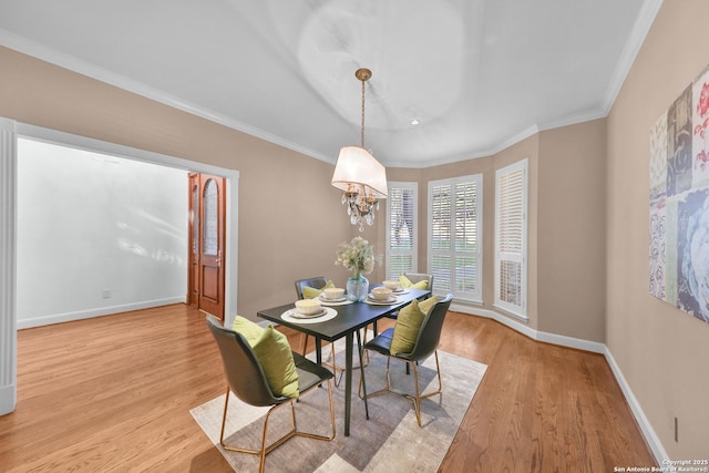 dining room with an inviting chandelier, light wood-style flooring, baseboards, and ornamental molding