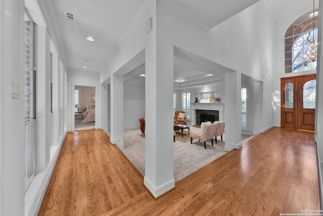 foyer entrance with visible vents, baseboards, crown molding, and light wood finished floors