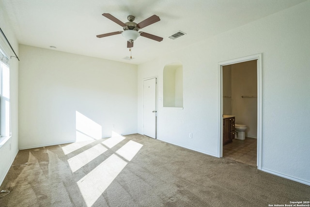 unfurnished bedroom with ceiling fan, visible vents, ensuite bath, and carpet flooring