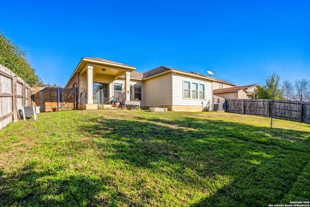 rear view of house with a fenced backyard, central air condition unit, and a yard