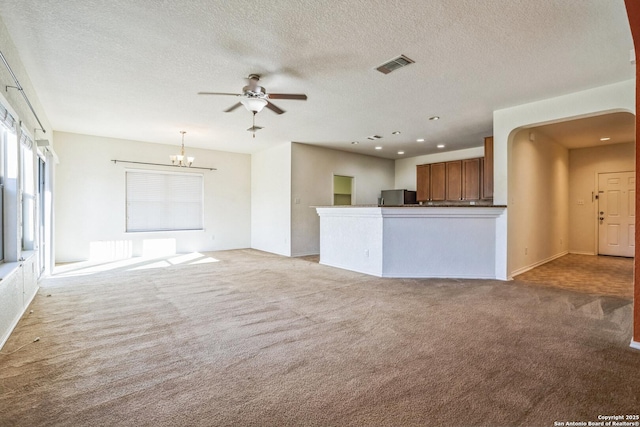 unfurnished living room with visible vents, ceiling fan with notable chandelier, a textured ceiling, recessed lighting, and light colored carpet