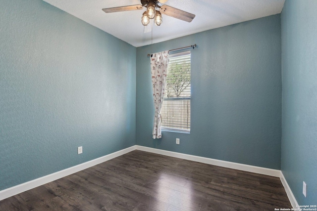 spare room featuring a ceiling fan, dark wood-style flooring, a textured wall, and baseboards