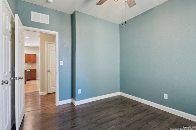 spare room featuring a ceiling fan, dark wood-style floors, visible vents, and baseboards