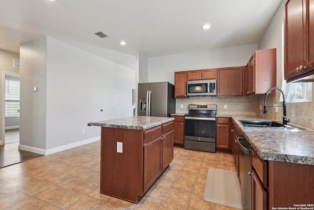 kitchen featuring visible vents, a kitchen island, decorative backsplash, appliances with stainless steel finishes, and a sink